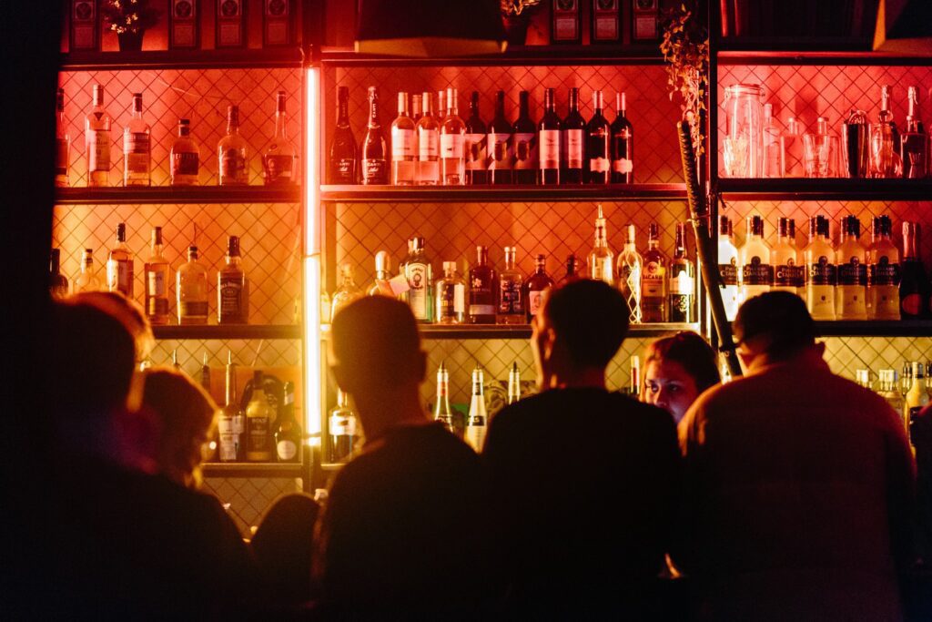 Bar Promotion Ideas; a crowd waiting at the bar counter with drinks placed on open shelves