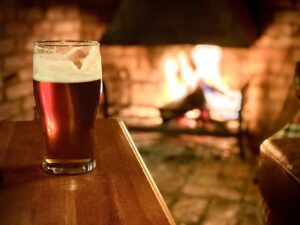 British pub culture guide; a drink placed on a wooden table near the fireplace
