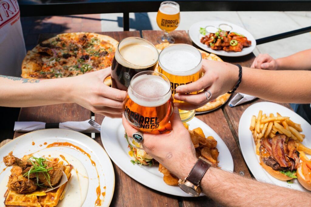 food and beer pairings; hands clinking beer glasses together.