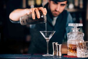 simple Christmas cocktail recipes; bartender pouring martini in the glass