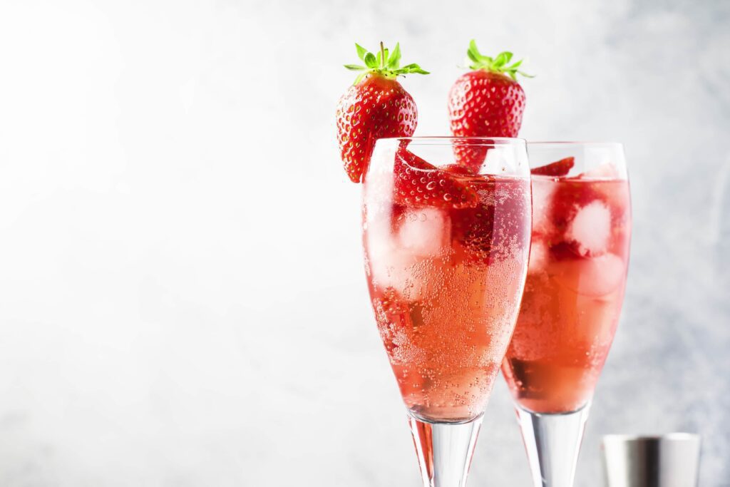 Valentine’s day cocktails, champagne flutes with red cocktails and strawberry garnish.