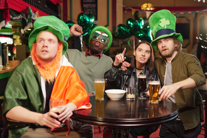 St. Patrick's Day Pub Games, people sitting at a pub table with green hats.