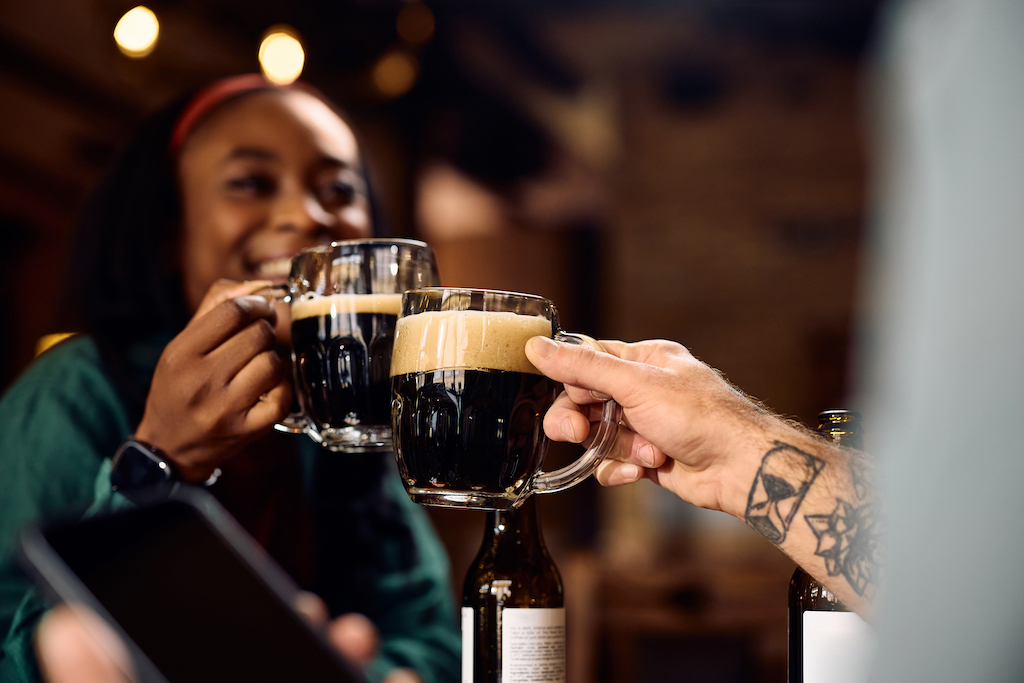 Irish drinks, two people toasting with mugs of dark beer.